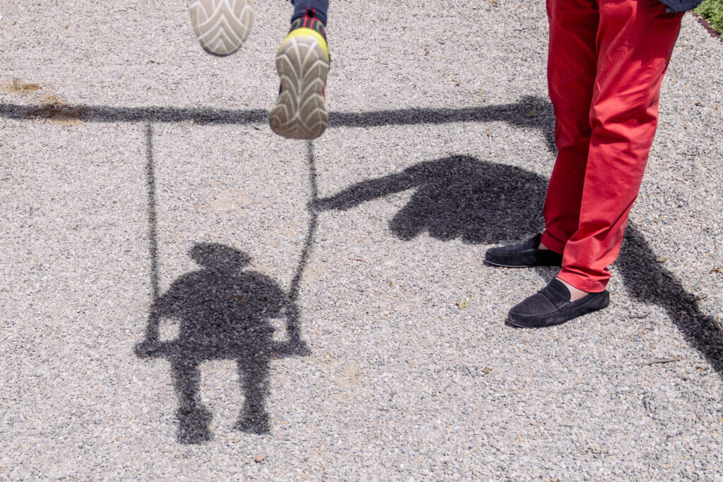 Kind auf Schaukel wirft Schatten beim Familienausflug