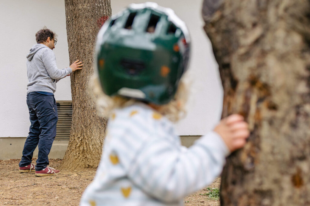 Papa spielt mit den Kindern verstecken in einem Park